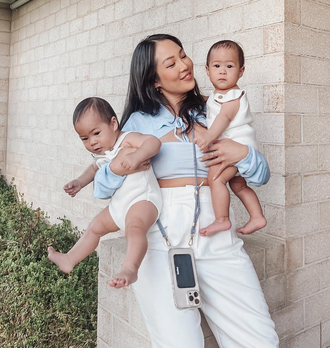 Mom holding her two babies while wearing a Keebos crossbody phone case hands-free