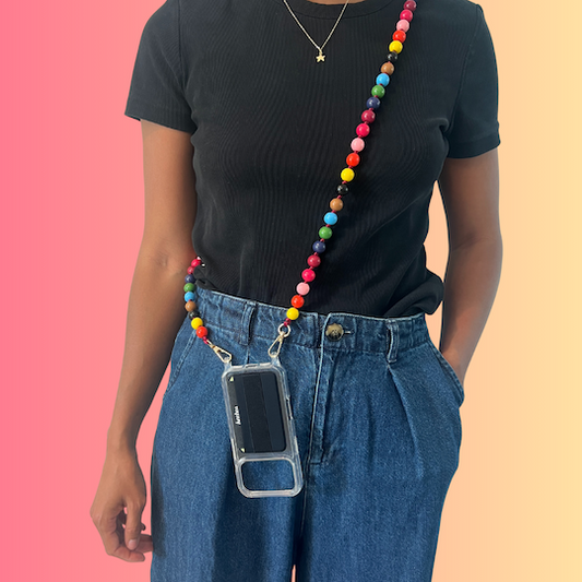 Person wearing a colorful beaded phone lanyard with a clear case on a pink and orange gradient background