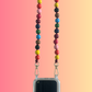 Colorful beaded phone lanyard with a clear phone case on a gradient background